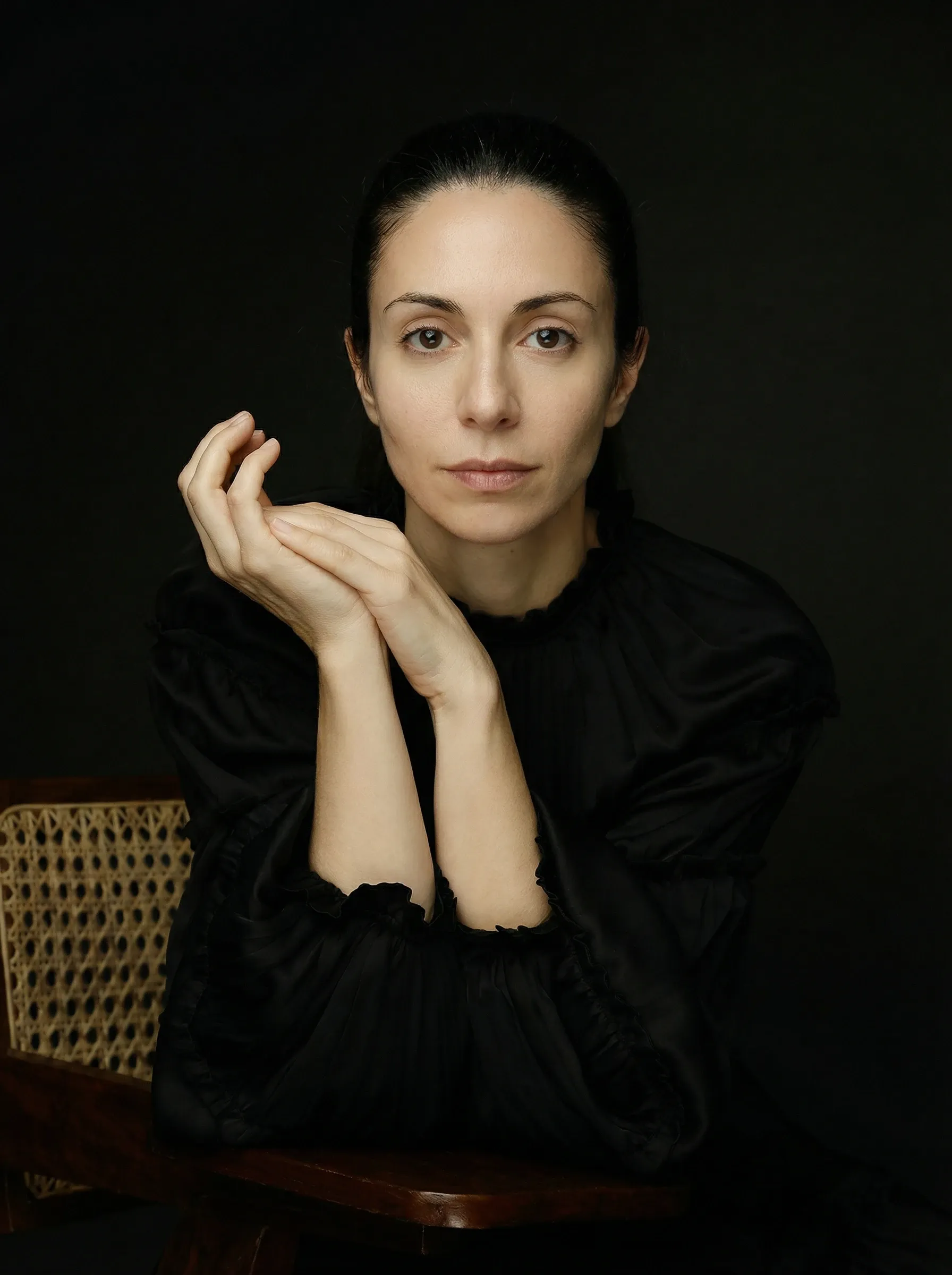 AI LinkedIn headshot — woman in a black blouse against a dark studio backdrop